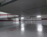 Suelo de garaje recién pintado, con líneas rojas y grises que marcan las plazas.