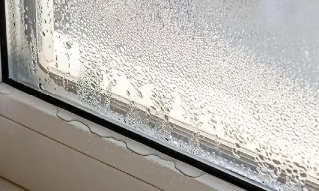 Ventana con gotas de agua, un claro ejemplo de condensación. El vapor de agua se ha adherido al cristal, formando pequeñas gotas que resbalan por el marco.