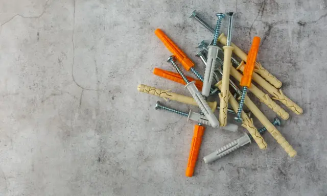 Montón de tacos de pared de varios colores (naranja, beige, gris) con tornillos. Listos para fijar cualquier cosa a la pared.