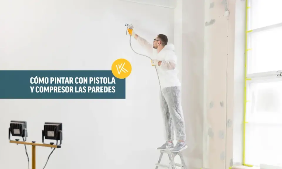 Hombre con traje protector pintando una pared con pistola y compresor.