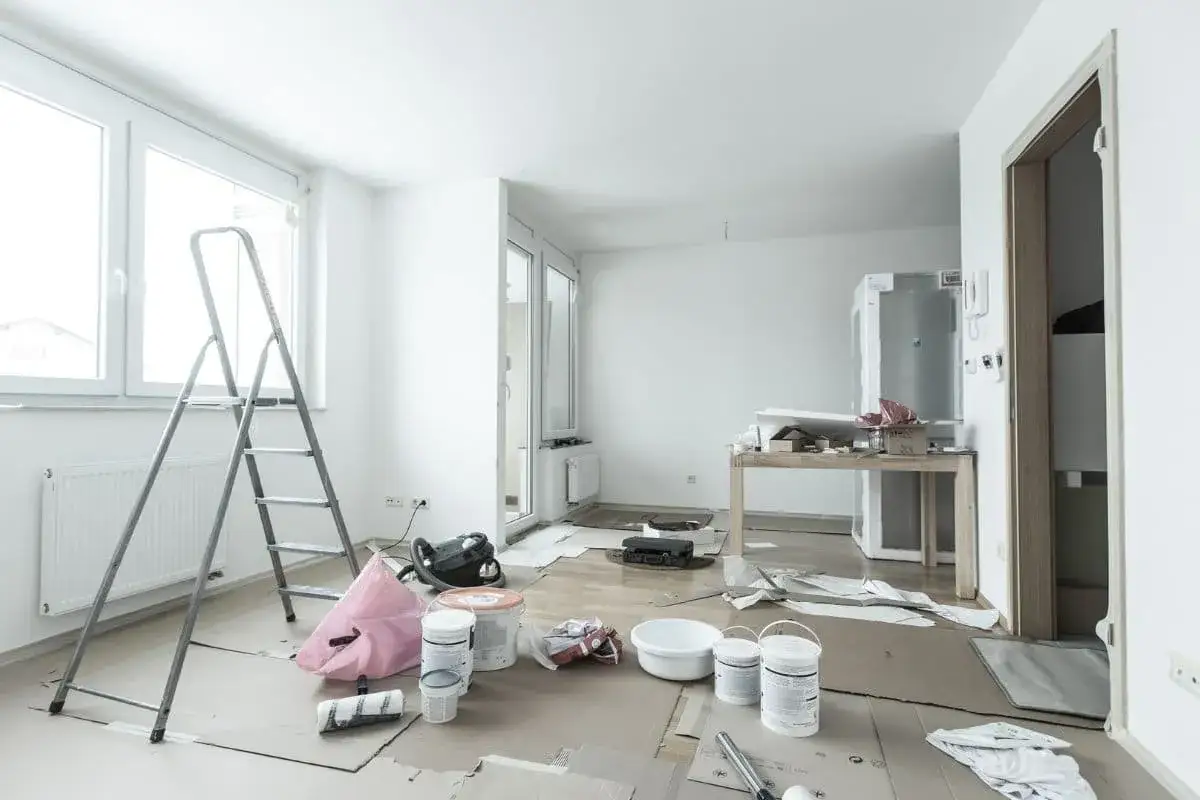Habitación en reforma con escalera, cubos de pintura y aspiradora. Preparando la casa para mejorar la eficiencia energética y solicitar deducciones IRPF.