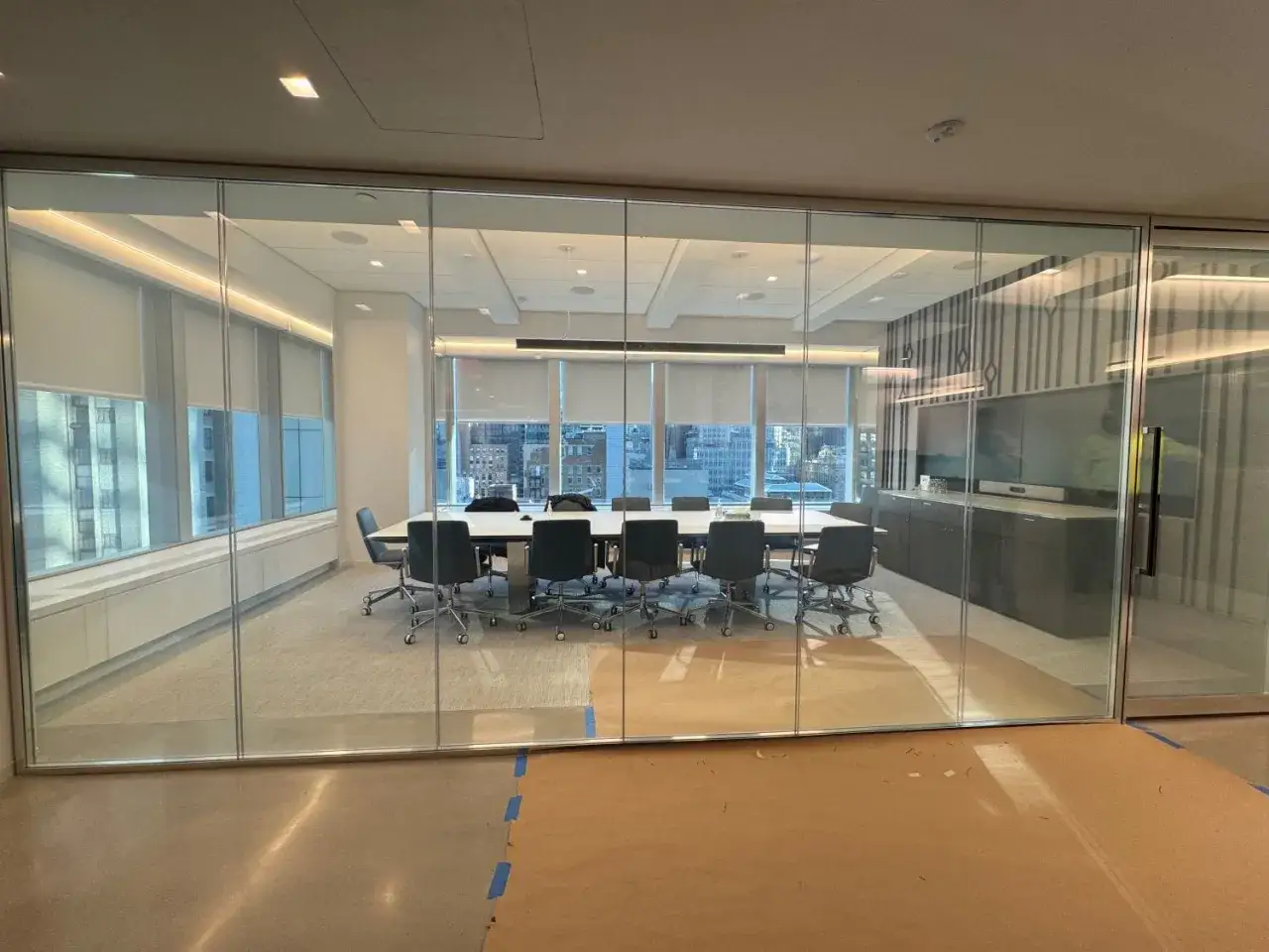 Sala de juntas moderna con mesa y sillas, rodeada por un cristal que se oscurece para mayor privacidad.