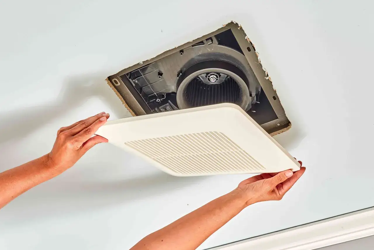 Manos colocando la cubierta de un extractor de baño.