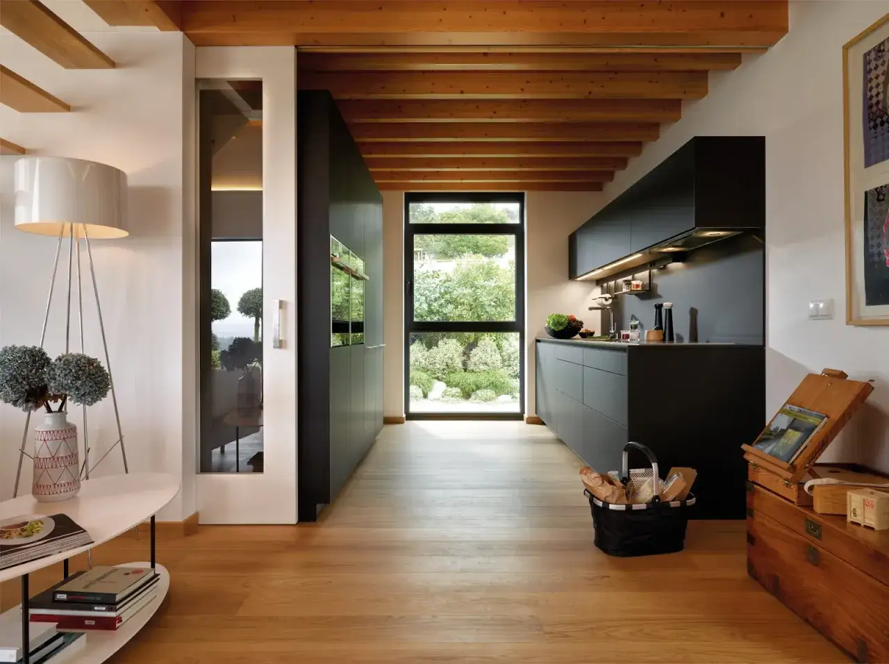 Cocina moderna con gabinetes negros, ventana grande y suelo de madera. Ideas para como diseñar una cocina funcional y elegante.
