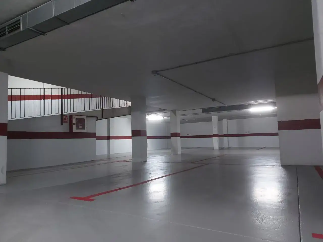 Suelo de garaje reci&eacute;n pintado con l&iacute;neas rojas, listo para estacionar.
