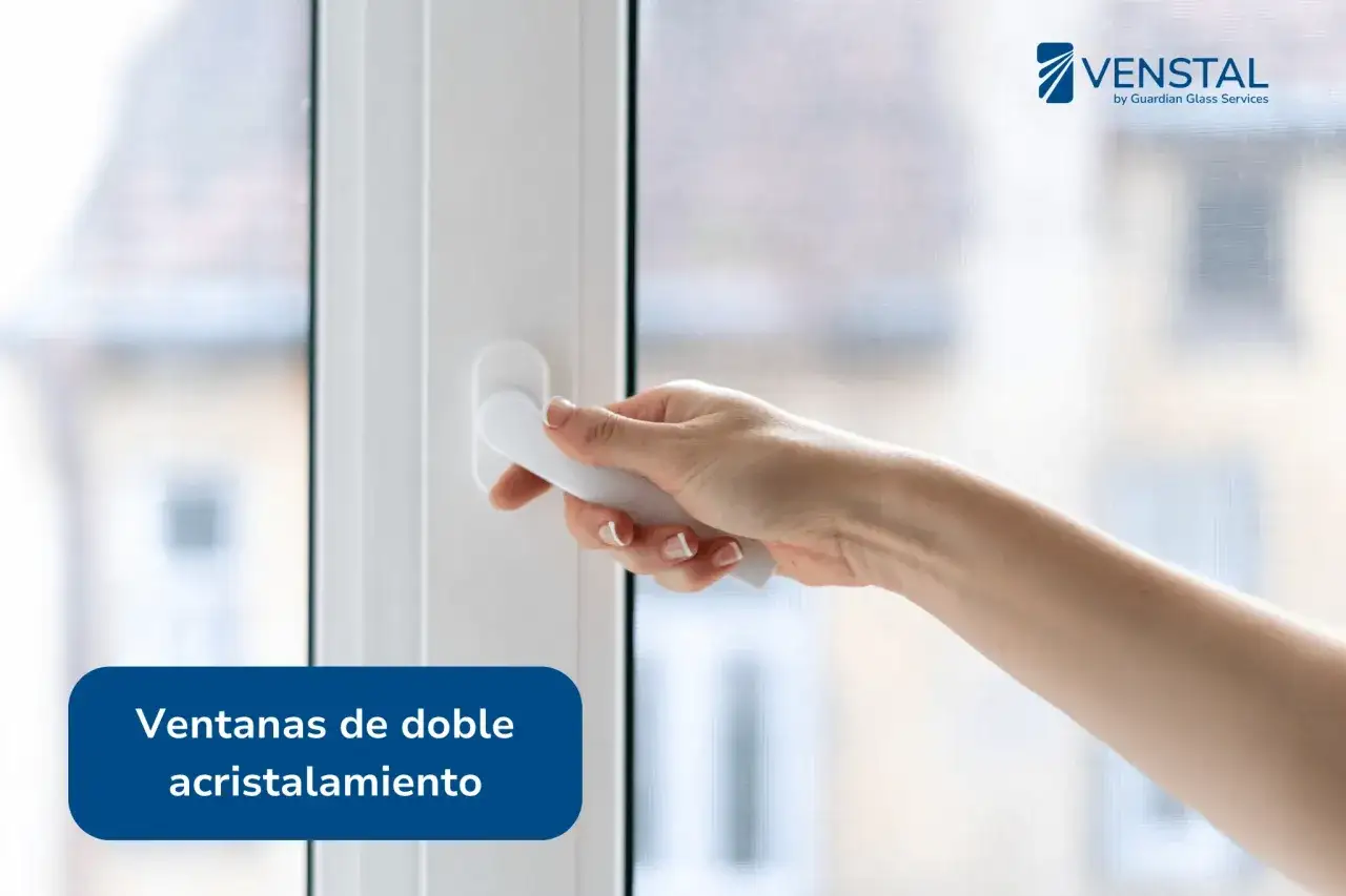 Mano abriendo una ventana con doble acristalamiento, que ofrece un excelente aislamiento térmico.