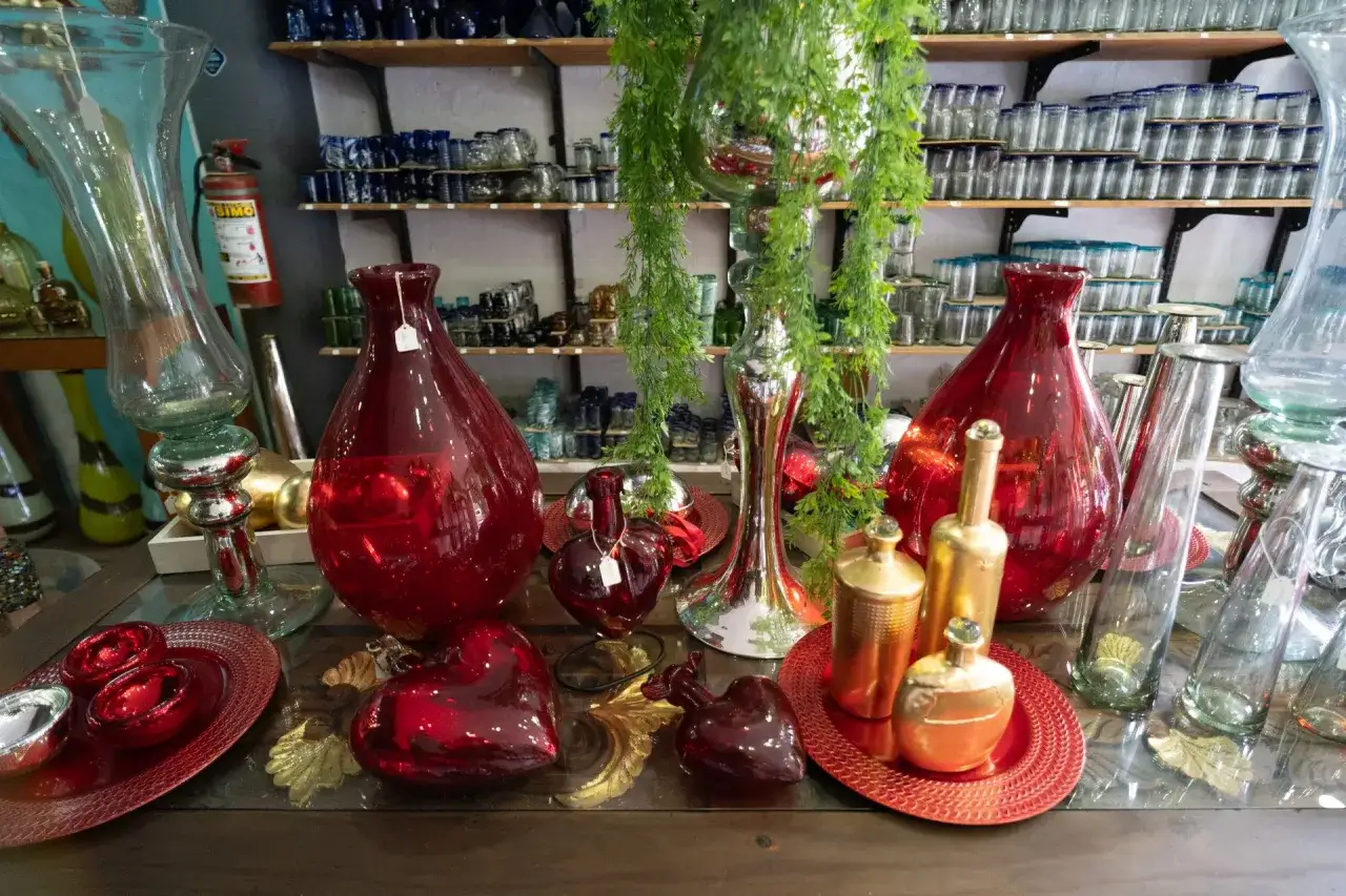 Jarr&oacute;n rojo brillante, corazones de vidrio y botellas doradas, parte de la historia del vidrio.