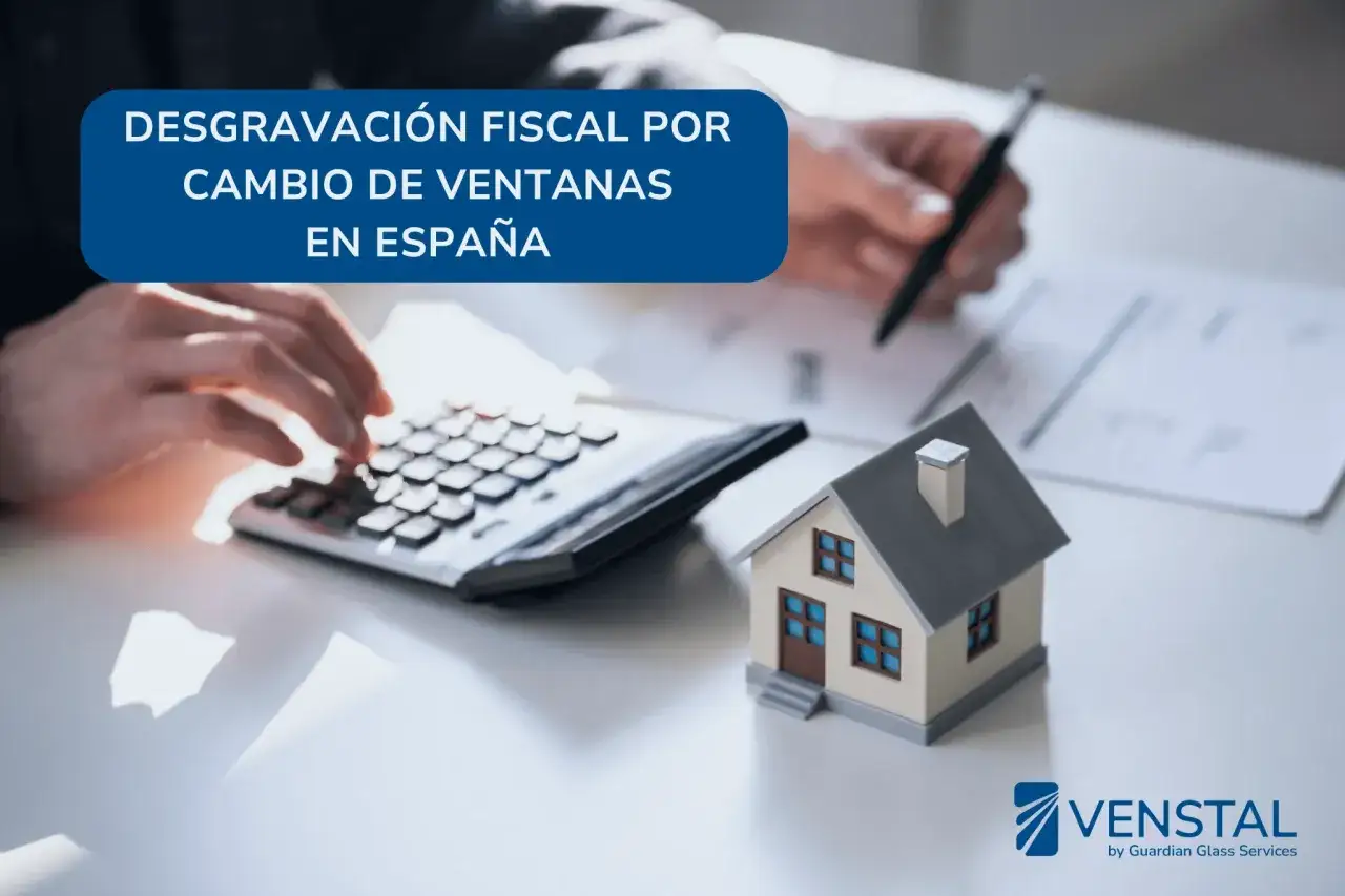 Manos calculando y escribiendo sobre c&oacute;mo se puede desgravar el cambio de ventanas en Espa&ntilde;a. Casa en miniatura y calculadora.